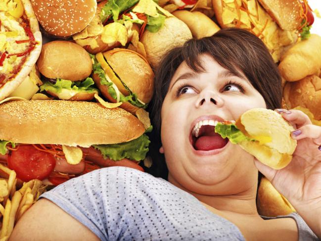 Una mujer en medio de comidas ricas en carbohidratos y azucares. Foto Thinkstock