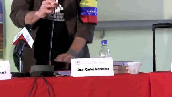 El fundador e ideólogo de Podemos, Juan Carlos Monedero Fernández con su brazalete chavista durante su ponencia. Imagen vídeo. Lasvocesdelpueblo