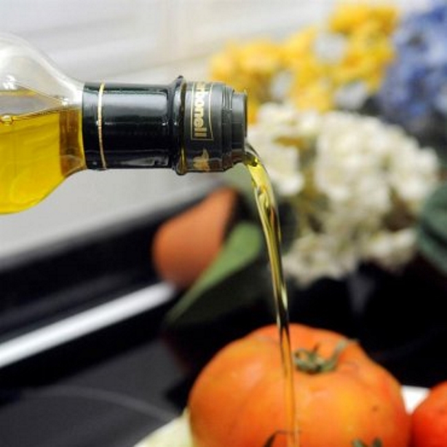 Una persona aliña con aceite de oliva una ensalada. Archivo Efe.