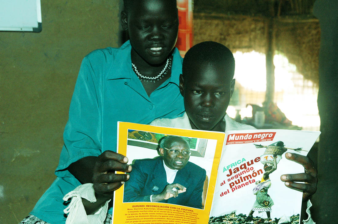 Dos joven africano subsahariano leyendo una noticia en lengua española del periodíco africano 'Mundo Negro' en una imagen de este medio. Lasvocesdelpueblo.