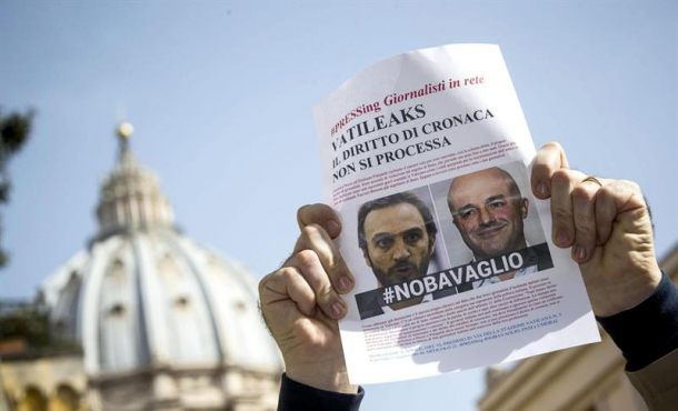 Un miembro de la Federación Nacional de la Prensa Italiana (FNSI) sostiene un cartel con la imagen de los periodistas italianos Gianluigi Nuzzi y Emiliano Fittipaldi... Archivo Efe