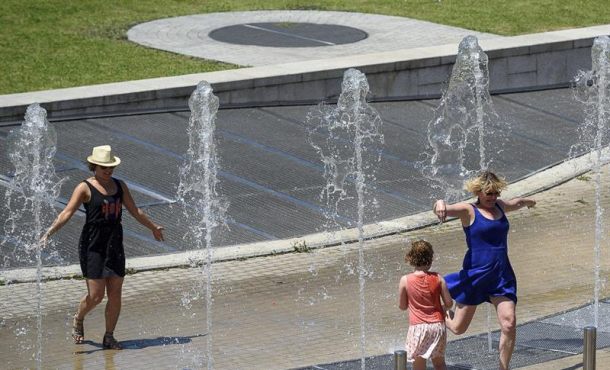 Varias personas disfrutan en una fuente de Bilbao para intentar mitigar las altas temperaturas registradas en la ciudad. EFE