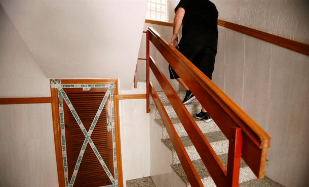 Una persona pasa junto al cuadro de contadores del edificio de Torrevieja donde fue encontrado ayer tapiado el cadáver de una mujer de origen chileno. EFE