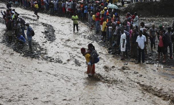 personas-intentan-cruzar-el-rio-la-digue-debido-al-derrumbe-del-unico-puente-que-conecta-con-el-sur-tras-el-paso-del-huracan-matthew-este-5-de-octubre-de-2016-en-petit-goave-haiti-efe