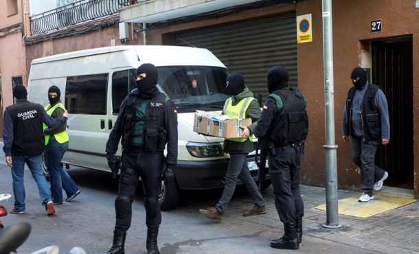 Agentes de la Guardia Civil portan documentación incautada en el domicilio de un ciudadano marroquí detenido por realizar actividades. Archivo Efe.