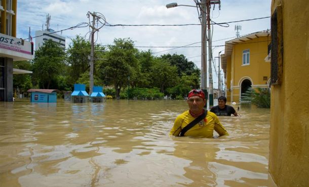 Dos hombres intentan cruzar una calle inundada por el río Piura este 27 de marzo de 2017, en Piura (Perú). Efe.