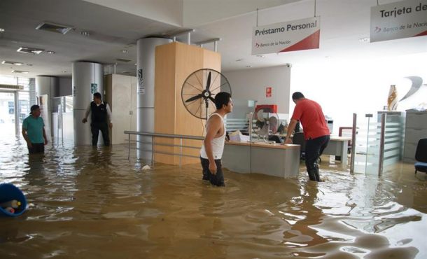Un grupo de personas camina por una de las oficinas del banco de la Nación, inundada por el río Piura, este lunes 27 de marzo de 2017, en Piura (Perú). Efe.