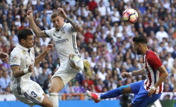 Los jugadores del Real Madrid Pepe (i) y Toni Kroos (c) disputan un balón con Yannick Carrasco (d), del Atlético de Madrid, durante el partido correspondiente. Efe