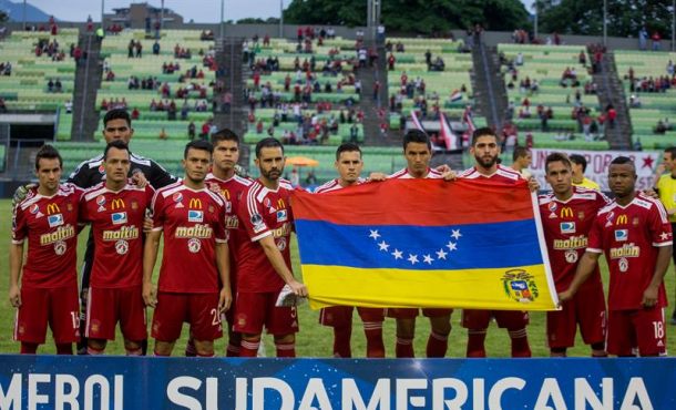 Jugadores del Caracas FC fueron registrados este jueves, 11 de mayo de 2017, al sostener una bandera venezolana al revés, antes de enfrentar al Cerro Porteño de Paraguay. Efe