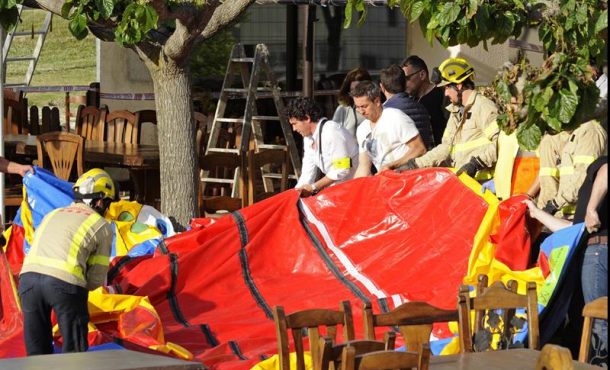 Varios operarios y bomberos retiran el castillo hinchable del restaurante Mas Oller, de Caldes de Malavella (Gerona), que ha volado unos 40m. Efe
