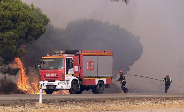 Bomberos intentan apagar un nuevo foco de fuego en la carretera que une las localidades de Mazagón y Matalascañas, en Huelva, en el incendio declarado ayer, domingo 25 de junio de 2017, Efe