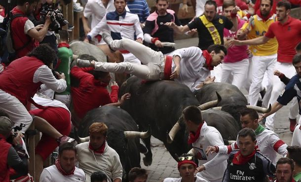 Los toros de la ganadería Miura voltean a un mozo en el tramo final que precede al callejón de entrada a la Plaza durante el octavo y último encierro de los Sanfermines 2017. Efe.