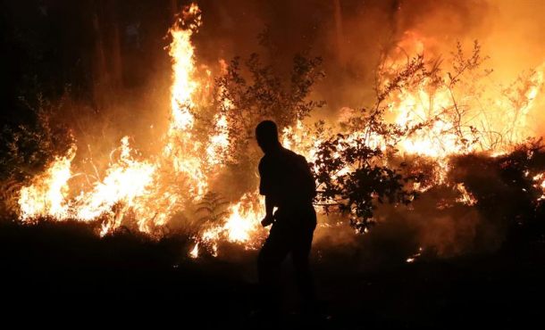 Bomberos y brigadas forestales de la junta de Galicia apagan en el lugar de Serra Dura, en A Rocha Vella, en las proximidades de Santiago de Compostela, un incendio forestal. Archivo Efe.