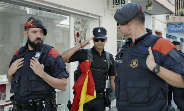 Un héroe de España, agente del Cuerpo Nacional de Policía, con la enseña nacional entre dos Mozos de Escuadra, a su salida del hotel. Efe.