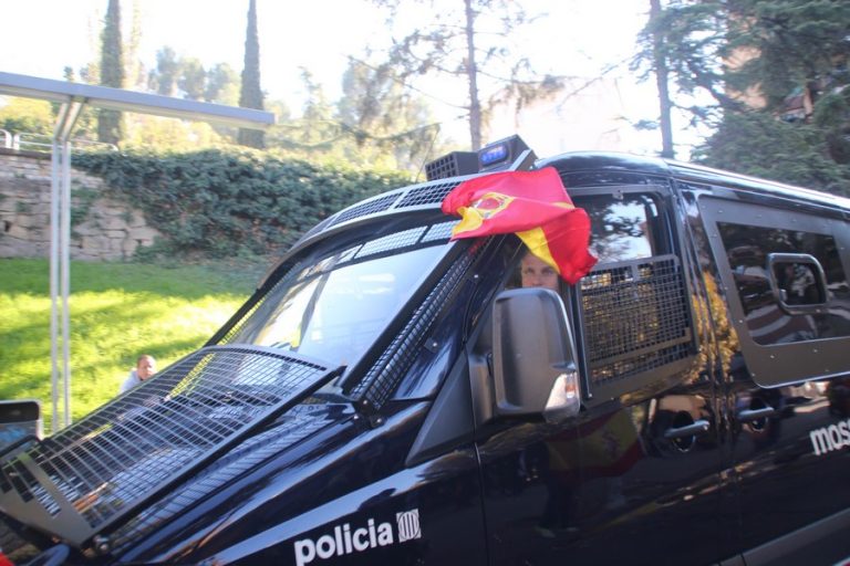 Un furgón de los Mozos lleva muy a su pesar a una bandera de España en Manresa (Barcelona)