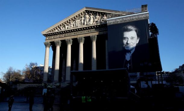 PARIS (FRANCIA), 9.12.2017. A portrait of the late French rock legend Johnny Hallyday hangs on the facade of the Madeleine Church ahead of the tribute ceremony. Efe