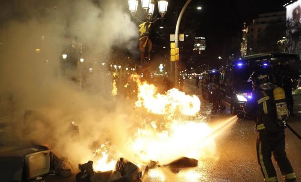 BARCELONA (ESPAÑA), 25.03.2018. Miembros del cuerpo de bomberos sofocan las llamas de los contenedores de basura incendiados en el Paseo de Gracia de Barcelona. Efe