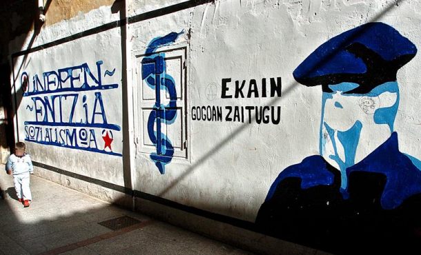 Un niño pasa junto a un mural que representa a un encapuchado junto al anagrama de ETA en la localidad guipuzcoana de Hernani. Archivo Efe