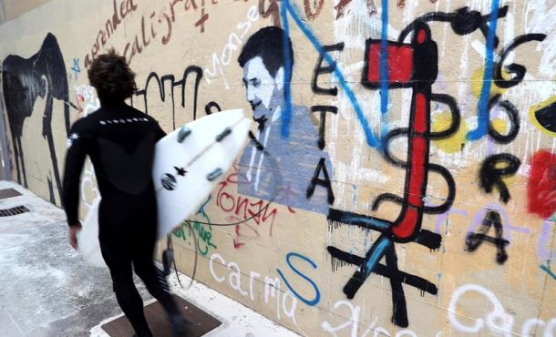 Un surfista pasa junto a una pintada a favor de la banda terrorista ETA en el barrio de Gros de San Sebastian, el pasado jueves.Efe