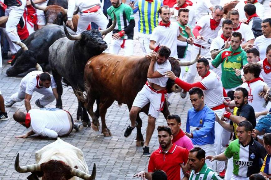 PAMPLONA (ESPAÑA), 14.07.2018. Un toro de la ganadería sevillana de Miura arrastra a un mozo a su paso por el tramo de Telefónica durante el octavo y último de los Sanfermines 2018. Efe