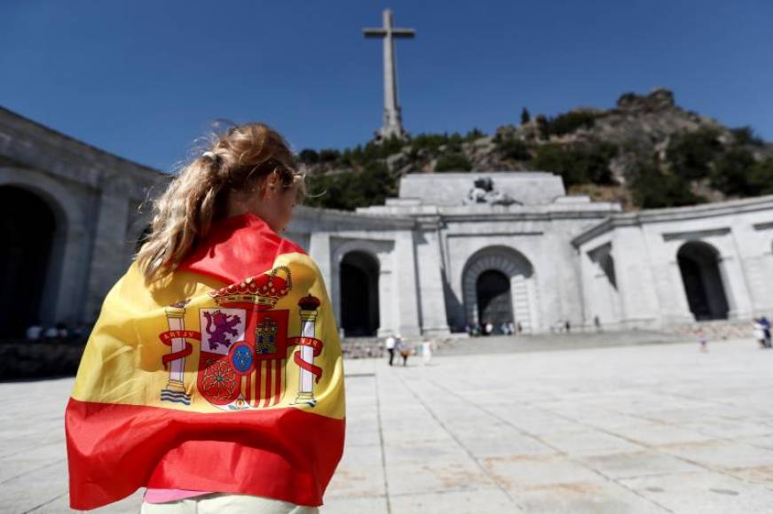 VALLE DE LOS CAÍDOS POR ESPAÑA 8MADRID), 21.08.2018. Una española envuelta en una bandera nacional de España en la explanada del Valle de los Caídos. Efe