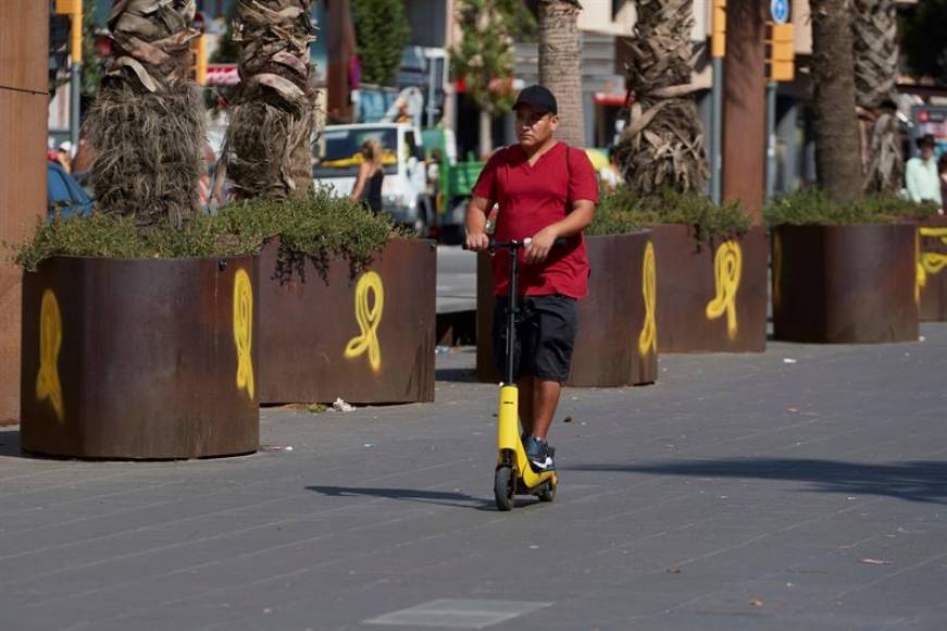CATALUÑA (ESPAÑA), 13.12.2018. Un hombre se desplaza con un patinete electrónico en una calle llena de pintadas separatista de forma de lazos amarillos del golpismo en Cataluña. Efe