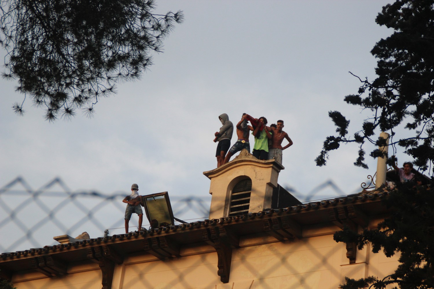 FOTOGRAFÍA. EL MASNOU (BARCELONA) ESPAÑA, 04.07.2019. Vista de un grupo de vecinas y vecinos de la localidad española de El Masnou (Barcelona). Ñ Pueblo (28) FOTOGRAFÍA. EL MASNOU (BARCELONA) ESPAÑA, 04.07.2019. Vista de un grupo de inmigrantes islamistas 'Menores no Acompañados (MENAS), unos cogiendo sus digitales y haciendo gestos obscenos mientras otros atancan con piedras a las vecinas y vecinos de la localidad española ubicada en la comarca de El Maresme (Barcelona), El Masnou, hoy desde el tejado del albergue donde están alojados por la generalidad de Cataluña y cobran '638 euros' mensuales, después del intento de agresión sexual de una joven de éste pueblo por parte de esos grupos de inmigrantes MENAS. Lasvocesdelpueblo