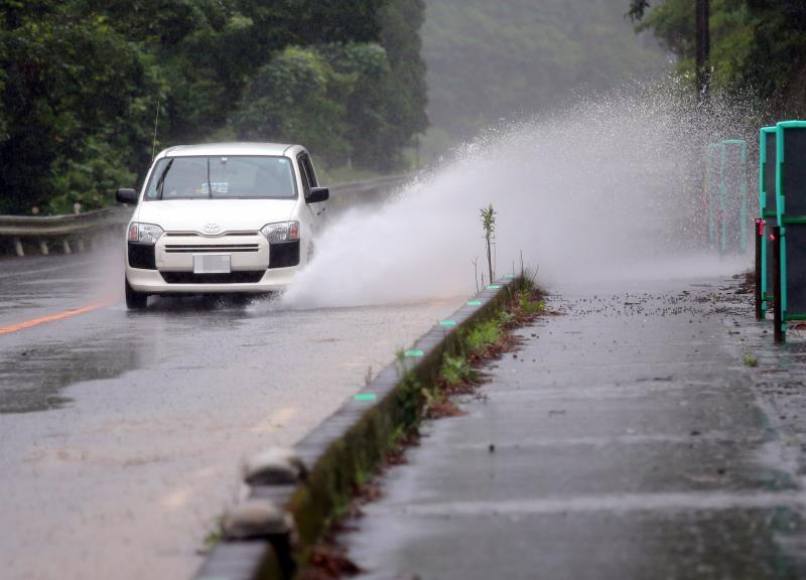 FOTOGRAFÍA. KUMAMOTO (JAPÓN), 03.07.2019. Un coche pasa por encima de un charco mientras circula por una carretera en Ashikita. Efe.