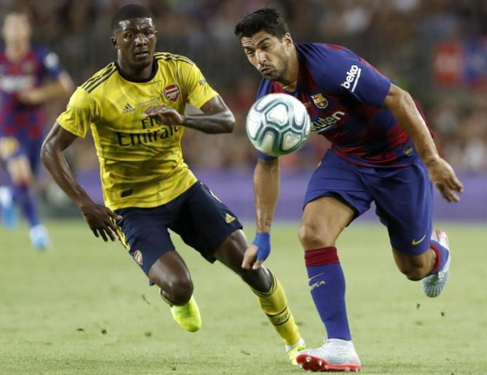 FOTOGRAFÍA. BARCELONA (ESPAÑA), 04.08.2019. El delantero del FC Barcelona Luis Suárez (d) pelea un balón con Ainsley Maitland-Niles, del Arsenal. Efe