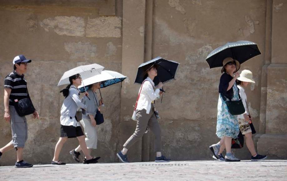 FOTOGRAFÍA. CÓRDOBA (ESPAÑA), 08.08.2019. Varios turistas se protegen con sombrillas del sol mientras pasean por el centro de Córdoba este lunes. Efe.