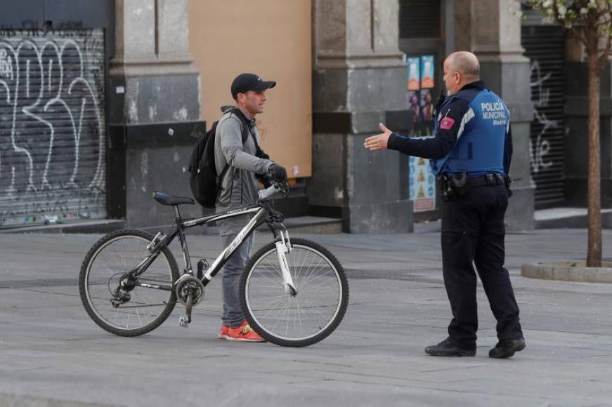 FOTOGRAFÍA. MADRID (ESPAÑA), 15.03.2020. Un policía informa en Madrid a un ciudadano de la prohibición de montar en bici tras la aprobación del estado de alarma. Efe