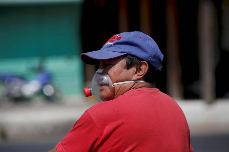 FOTOGRAFÍA. ANTIGUA GUATEMALA (GUATEMALA), 10.04.2020. Un hombre con una mascarilla improvisada con una envase de gaseosa pasa frente a la fachada de la iglesia San Felipe. Efe