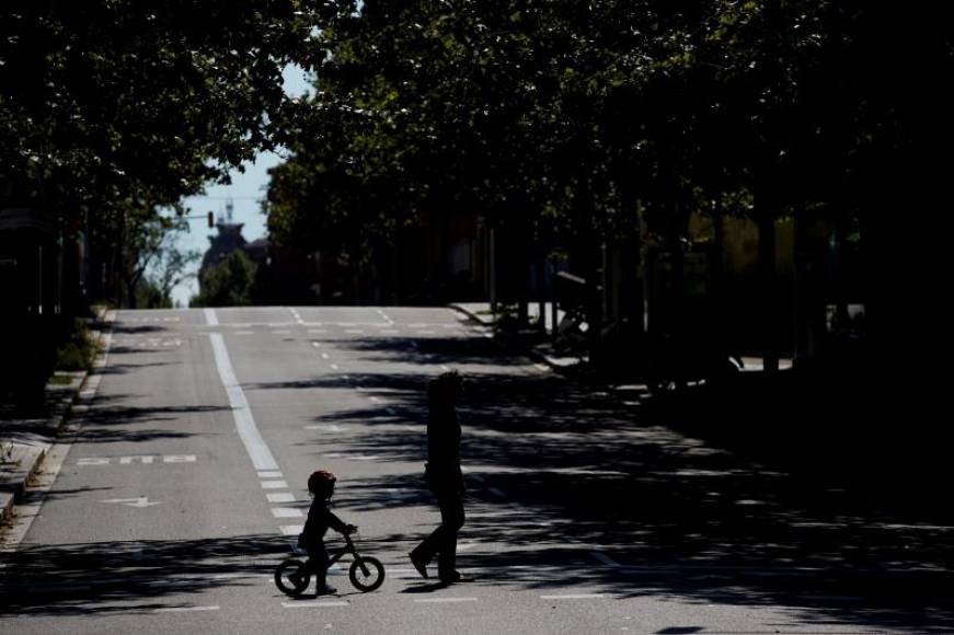 FOTOGRAFÍA. BARCELONA (ESPAÑA), 25.04.2020. Un menor en bicicleta detrás de un familiar durante el confinamiento por covid 19 en Cataluña. Efe