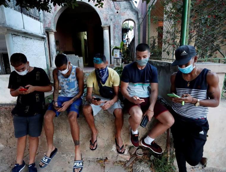 FOTOGRAFÍA. LA HABANA (CUBA), 07.04.2020. Un grupo de jóvenes con tapabocas fue registrado este lunes al mirar sus teléfonos celulares en un barrio de La Habana (Cuba). Efe