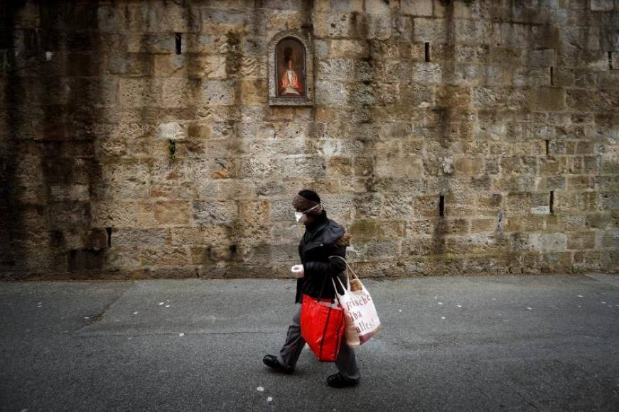 FOTOGRAFÍA. PAMPLONA (ESPAÑA), 21.04.2020. Una mujer pasa por delante de la hornacina de San Fermín en la cuesta de Santo Domingo de Pamplona. Efe