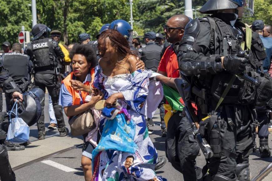 FOTOGRAFÍA. GINEBRA (SUIZA), JUNIO DE 2018. La policía trataba de proteger a una mujer con un vestido adornado con fotos del presidente de Camerún, Paul Biya. Efe