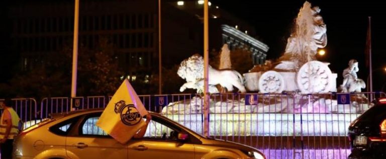 Los madridistas a pie y coches, tocando el claxon en señal de alegría, en la fuente de Cibeles