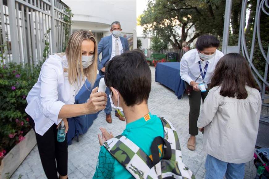 FOTOGRAFÍA. ESPLUGUES DE LLOBREGAT (BARCELONA), SEPTIEMBRE DE 2020. Una trabajadora toma la temperatura a un niño a la entrada del colegio privado internacional American School. Efe