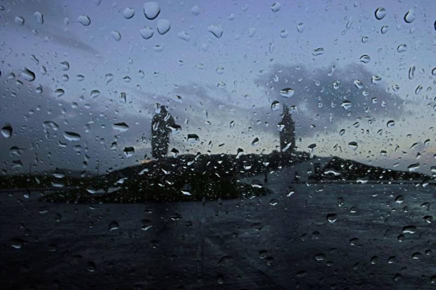 FOTOGRAFÍA. LA CORUÑA (ESPAÑA), 28.12.2020. La Torre de Hércules y la estatua de Breogán vistas tras un cristal salpicado de gotas de lluvia este lunes en el que la borrasca Bella. Efe