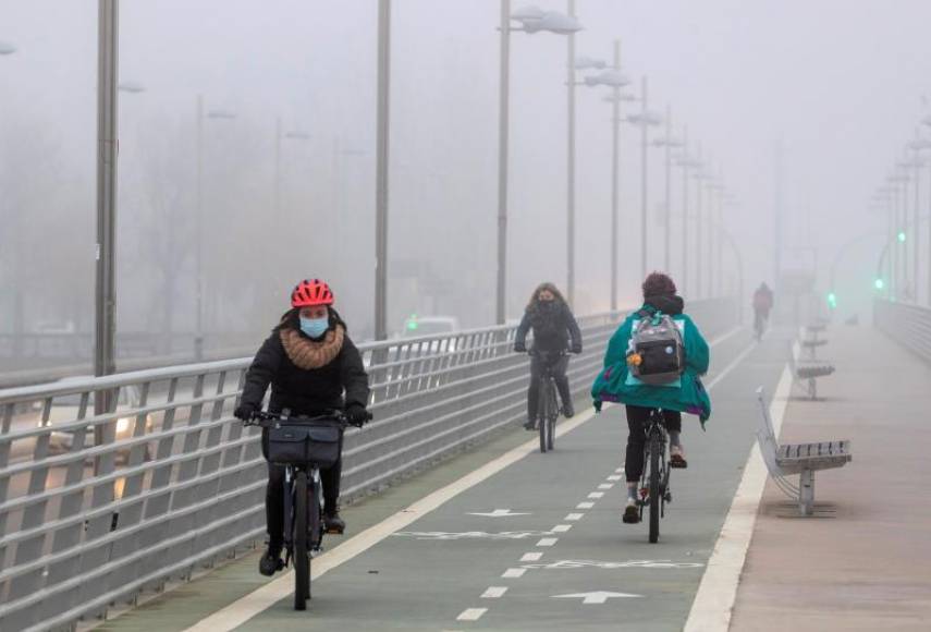 FOTOGRAFÍA. ZARAGOZA (ESPAÑA), 18.12.2020. Viandantes caminan entre la niebla por los aledaños del rio Ebro en Zaragoza, este viernes. Efe