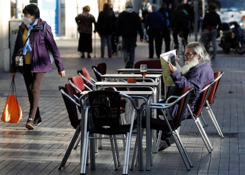 Una persona lee la prensa entre sillas en la terraza de un bar de la Comunidad autónoma de Cataluña tras el cierre encubierto dictado. Efe