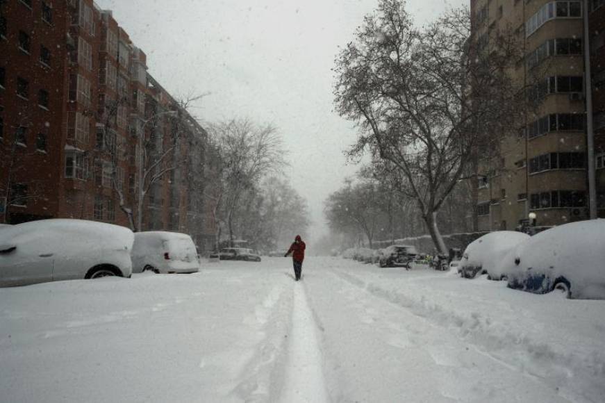 FOTOGRAFÍA. MADRID (ESPAÑA), 09.01.2021. Viandantes por una calle cubierta de nieve en Madrid, este sábado. Efe