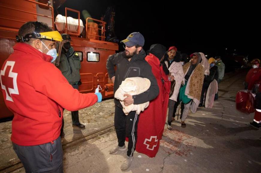 FOTOGRAFÍA. MOTRIL (ESPAÑA), 26.03.2021. Miembros de la Cruz Roja ayudan a su llegada esta madrugada al puerto de Motril (Granada) a 16 inmigrantes ilegales magrebíes. Efe