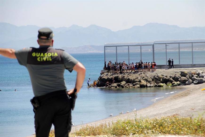 FOTOGRAFÍA. CEUTA (ESPAÑA), 17.05.2021. Un agente de la Guardia Civil observa a inmigrantes marroquíes. Efe