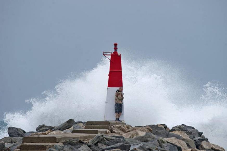 FOTOGRAFÍA. CASTELLÓN DE AMPURIAS (GERONA) ESPAÑA, 19.05.2021. Un turista se protege del oleaje tras una luz de señalización del Puerto Deportivo de Ampuriabrava. Efe