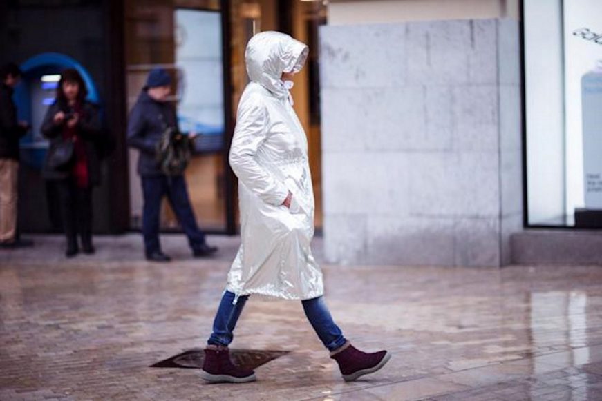 FOTOGRAFÍA. MÁLAGA (ESPAÑA), 29.03.2022. Una persona se resguarda de la lluvia con un chubasquero mientras pasea hoy por una calle del centro de Málaga. Efe