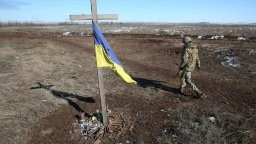 FOTOGRAFÍA. SVETLODARSK (UCRANIA), 12.03.2022. Un soldado ucraniano pasa junto a un memorial improvisado en Svetlodarsk en Ucrania. Afp