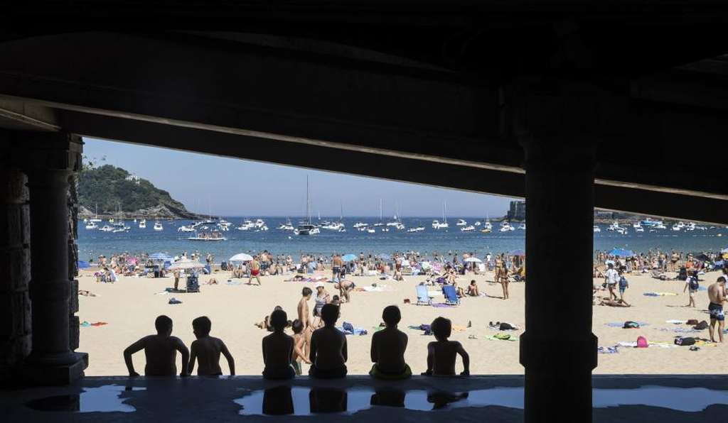 FOTOGRAFÍA. SAN SEBASTIÁN (ESPAÑA), 12.07.2022. Varios niños buscan la sombra en la playa de La Concha de San Sebastián, donde los cielos . Efe