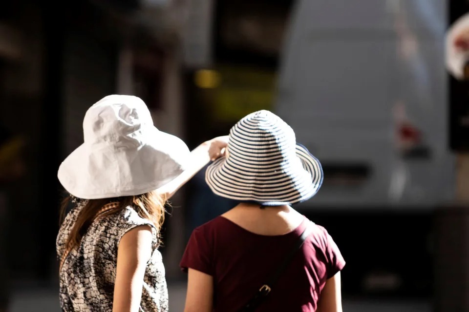 FOTOGRAFÍA. TOLEDO (ESPAÑA), 04.2022. Dos mujeres se protegen del sol con sombreros en Toledo. Efe