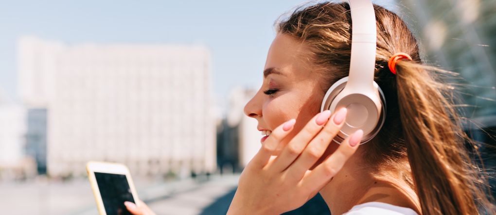 FOTOGRAFÍA. MUNDO, 06.10.2022. Detalle de una mujer joven escuchando música en auriculares y navegando por internet desde su teléfono inteligente, Smartphone. Freepik. Ñ Pueblo